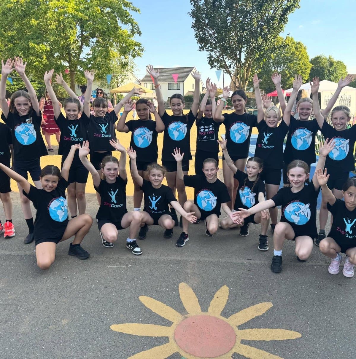 Group of children at a summer dance event outdoors, smiling and dancing together