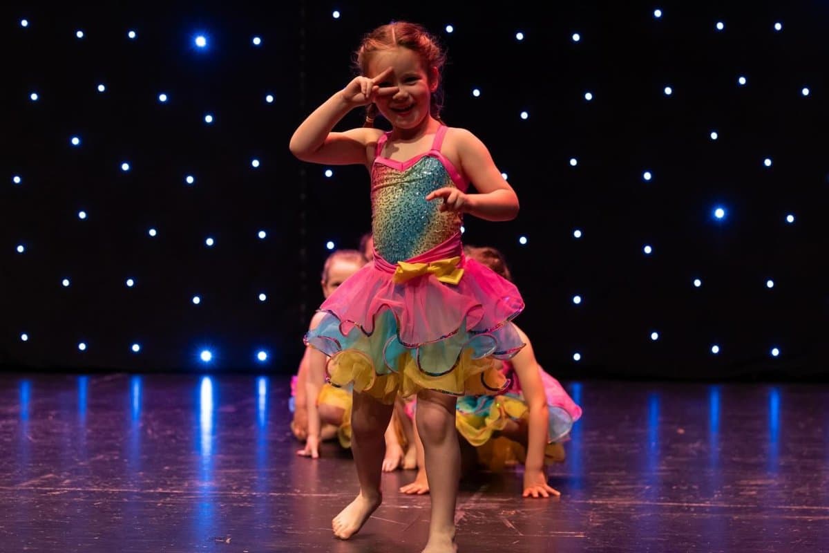 Young dancer in a rainbow tutu solo on stage