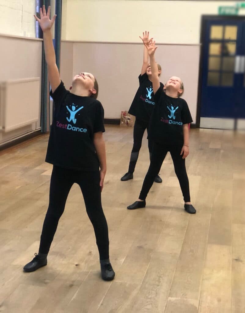 Children in Zest Dance t-shirts reaching up in dance class